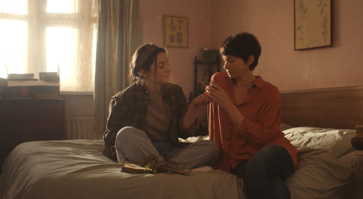 A teenage girl and a woman sit on a bed in “You Are Not My Mother.” 
