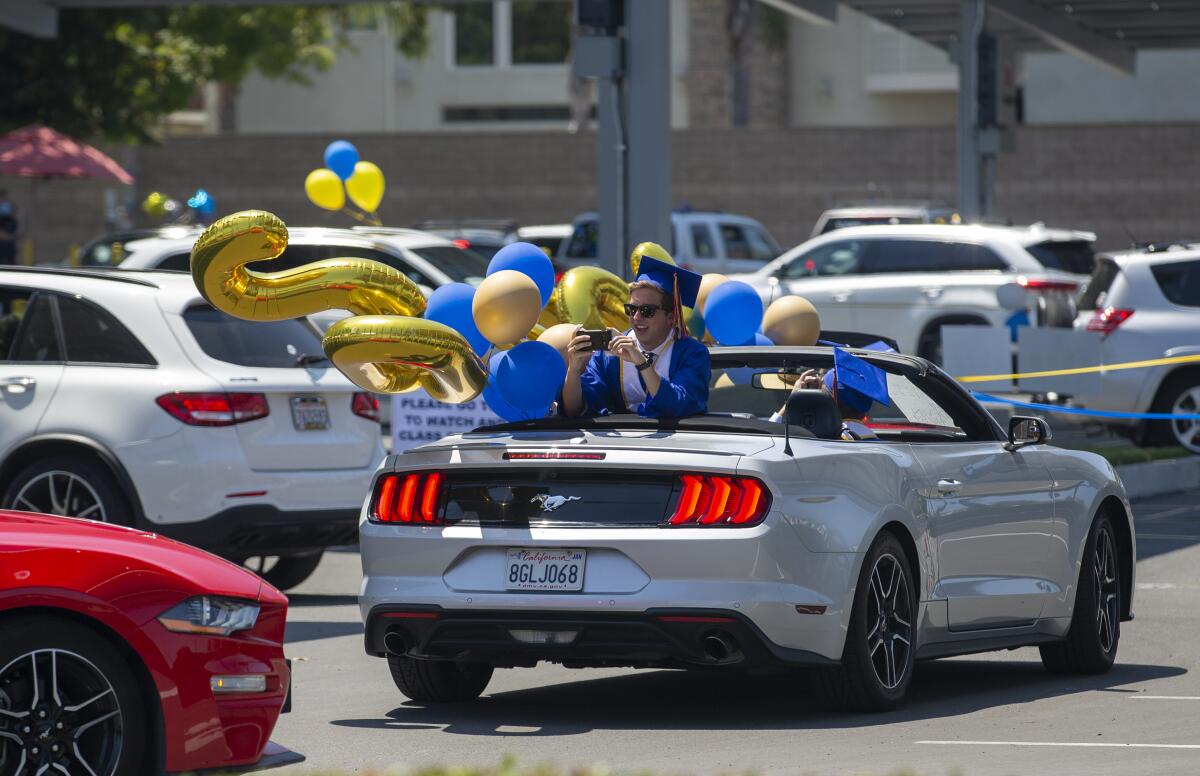 A graduate takes a picture during a drive-through graduation at Fountain Valley High School on Wednesday.