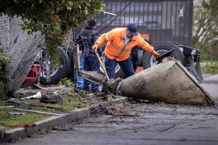 Montebello, CA - March 22: Clean up crews remove a large piece of debris that was strewn along Maple Ave. following a strong microburst -- which some witnesses dubbed a possible tornado -- at the scene where one person injured nearby and heavily damaged several cars and roofs of several buildings Wednesday, March 22, 2023. Five buildings have been damaged and one has been red-tagged. Video from the scene showing portions of rooftops being ripped off industrial structures and debris swirling in the air. The National Weather Service on Tuesday night issued a brief tornado warning in southwestern Los Angeles County, but it was allowed to expire after about 15 minutes when weather conditions eased. There was no such warning in place late Wednesday morning when the powerful winds hit Montebello, near the area of Washington Boulevard and Vail Avenue. (Allen J. Schaben / Los Angeles Times)