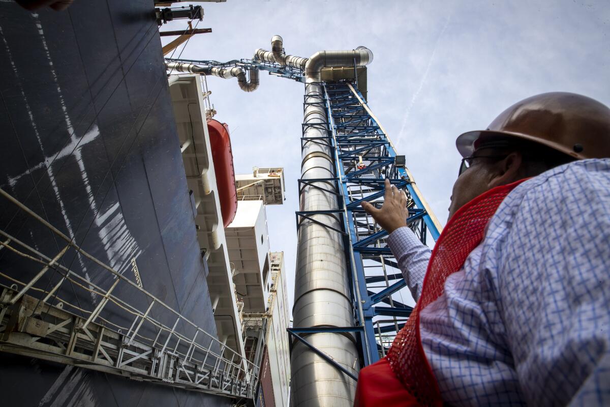 Ruben Garcia, president of Advanced Environmental Group, points out the telescoping tube of an emissions capture system that's attached to a barge at the Port of L.A.