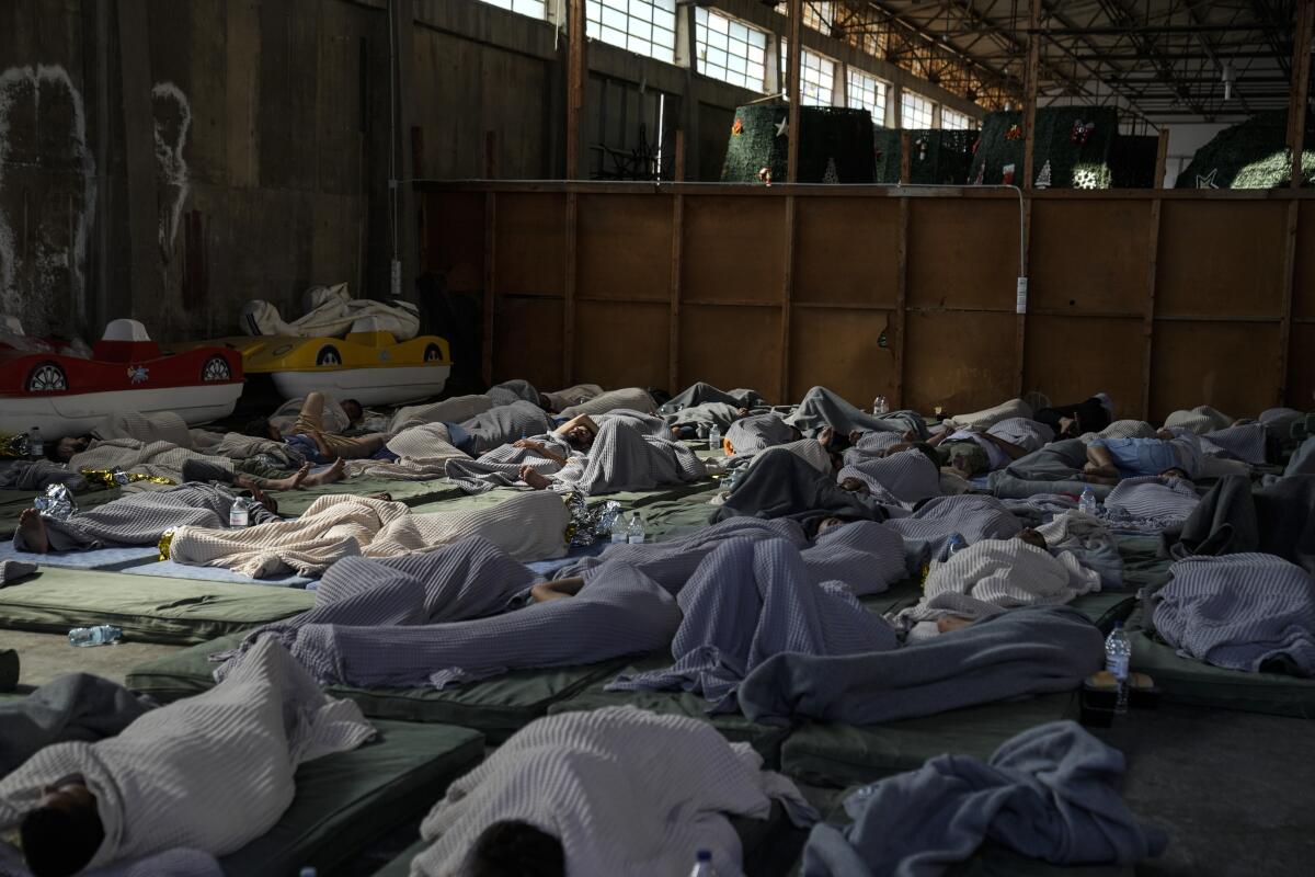 Survivors of a shipwreck sleep at a warehouse.