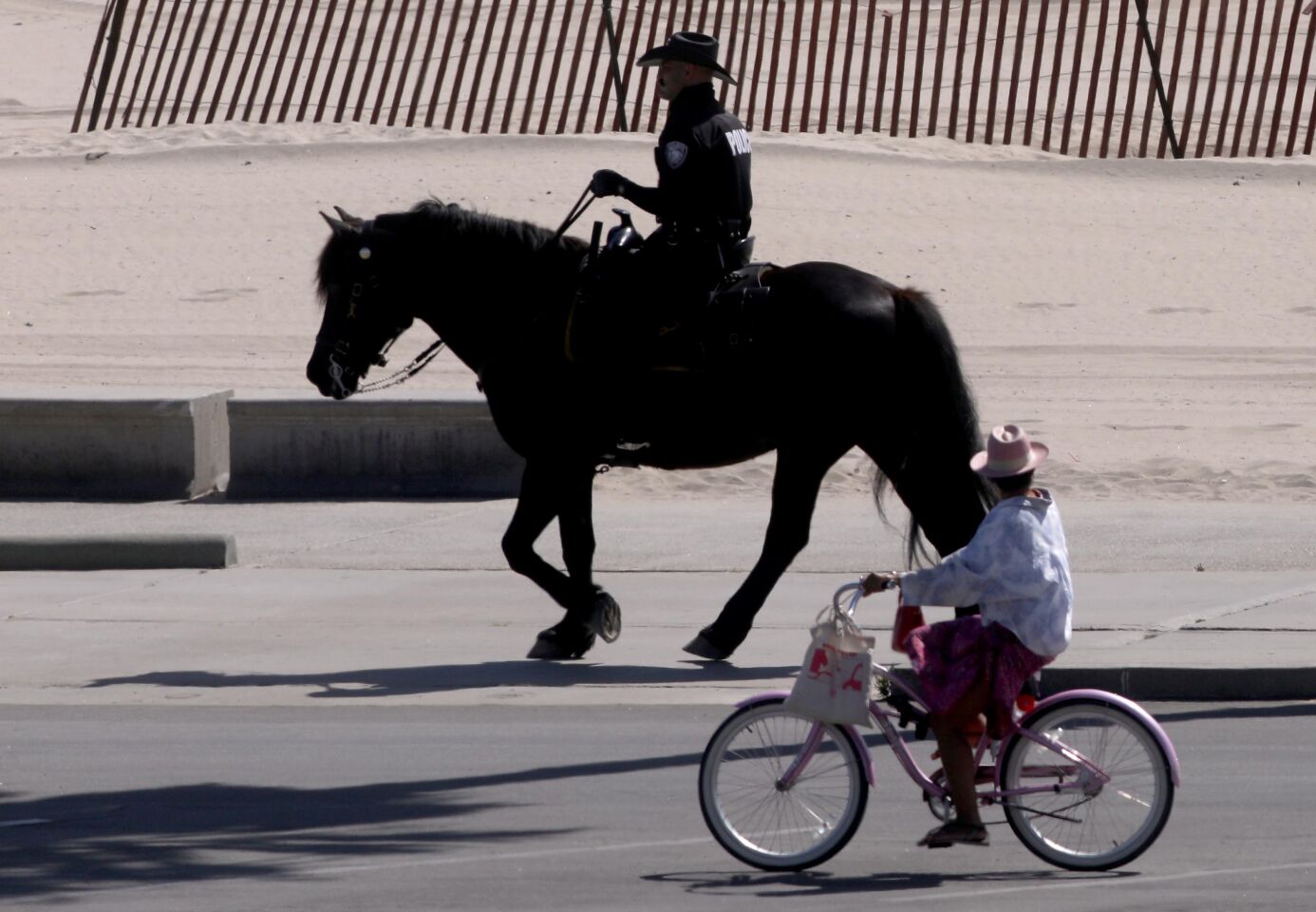 A woman rides a bike past a mounted police officer in Santa Monica on Wednesday.