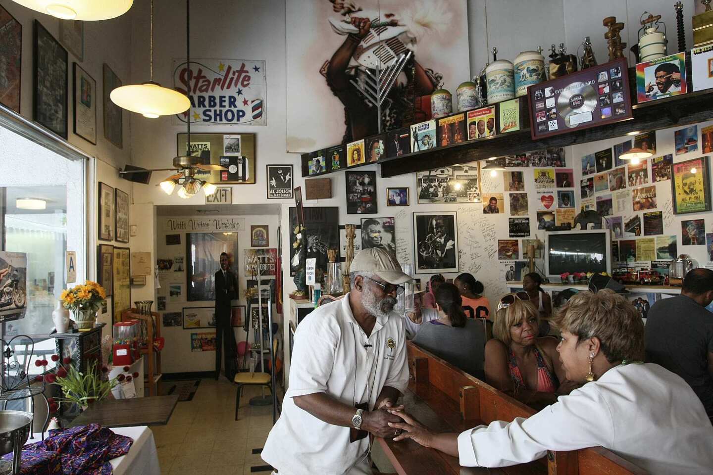 Desiree E. Edwards, (right, seated) owner/manager of the Watts Coffee House, greets Harold Hambrick at the shop in the Watts area of Los Angeles. Desiree has owned the coffee house since the mid-1990s.