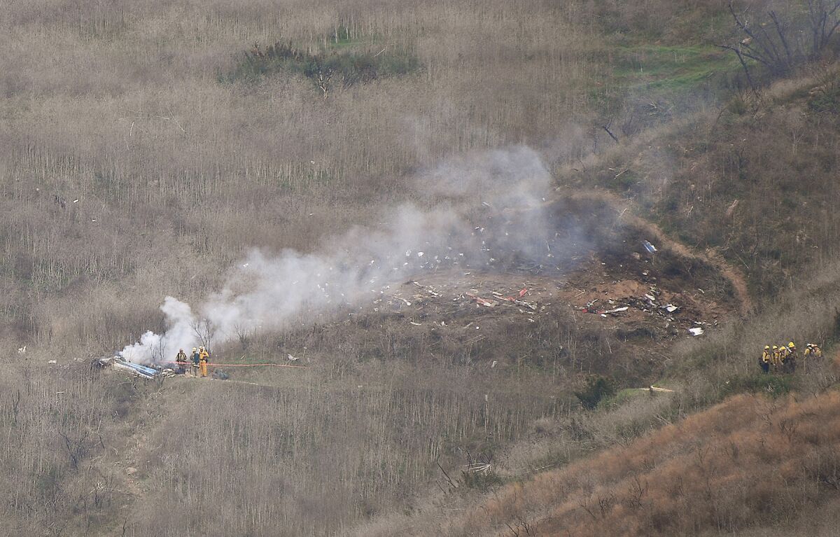 Smoke rises from wreckage on a hillside.
