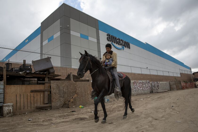 Tijuana, Baja California - October 18: Fernando Guevera, 17, and his sister, Karina, 2, ride a horse in Colonia Nueva Esperanza on Monday, Oct. 18, 2021 in Tijuana, Baja California. Amazon recently opened a $21 million dollar warehouse neighboring the Colonia. Many residents are use to living by industry since there are two other large facilities on either end of Amazon.(Ana Ramirez / The San Diego Union-Tribune)