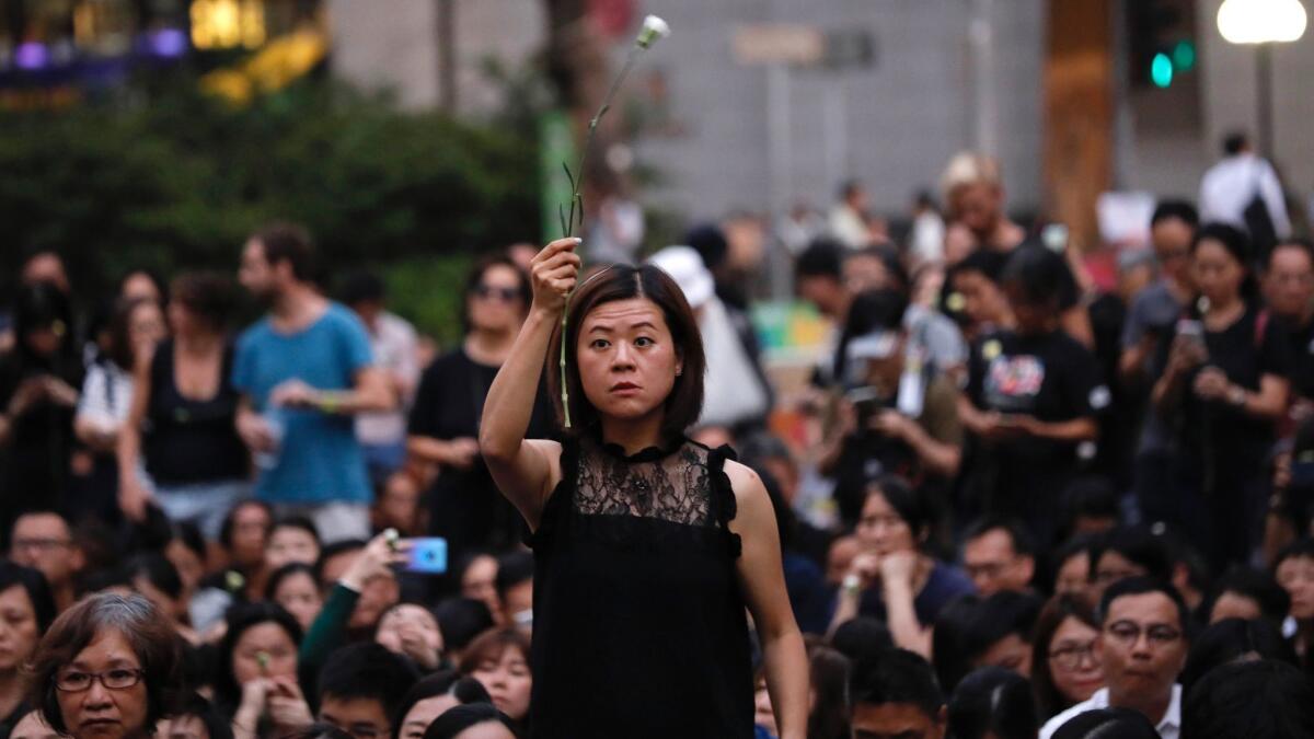 A woman holds a flower as she joins hundreds of mothers protesting against the amendments to the extradition law after Wednesday's violent protest in Hong Kong on Friday, June 14, 2019.