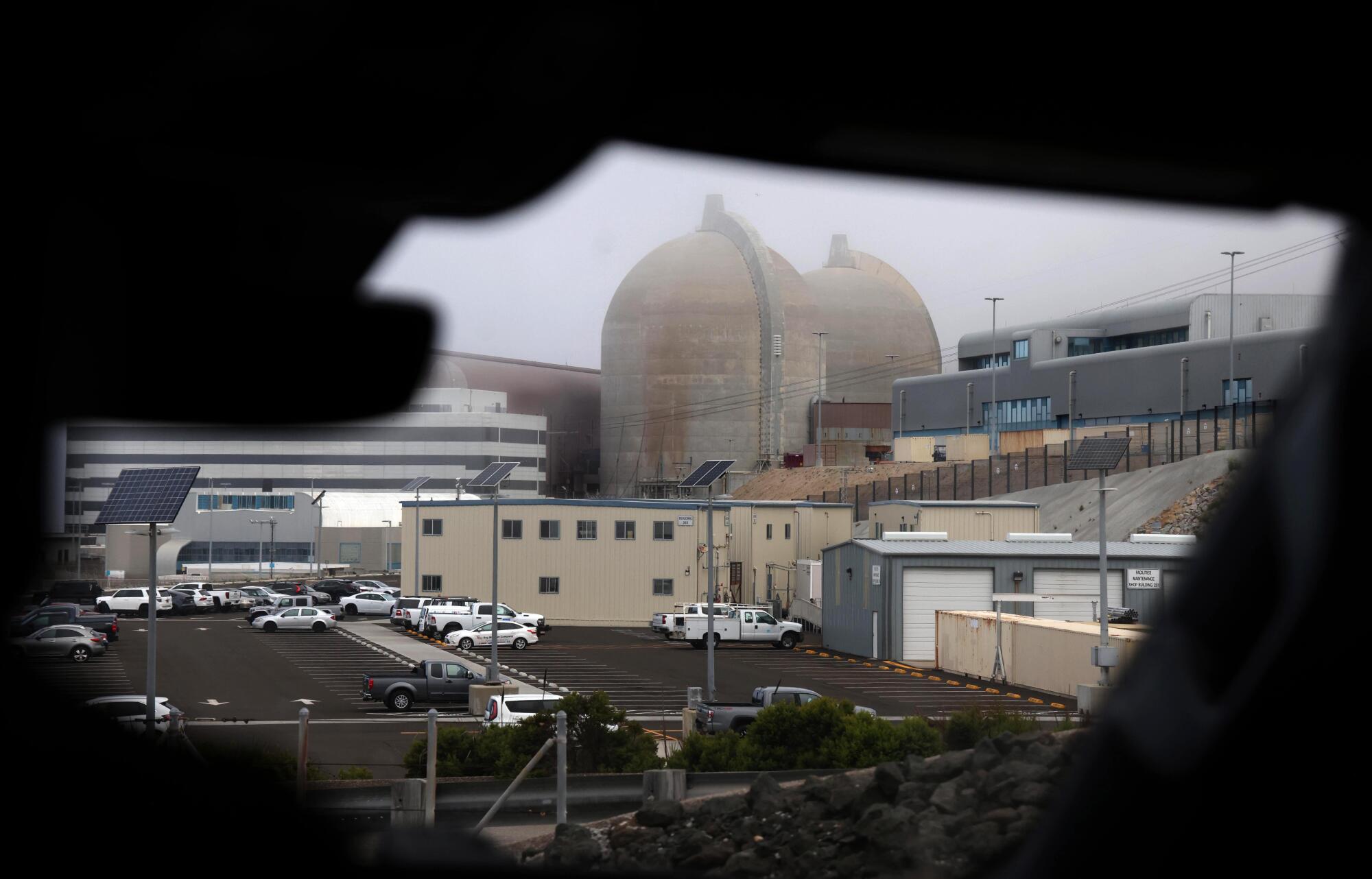 Fog rises behind twin containment domes at a nuclear power plant.