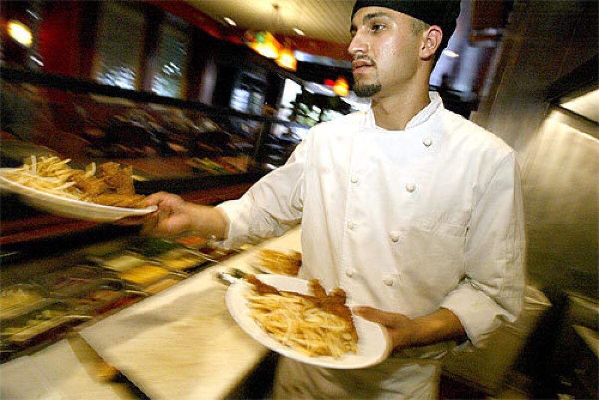 CULINARY SALVATION: Chef Rigo Salas dishes up a couple of chicken-and-fries dinners at Lot 1224, the restaurant inside the Loews Beverly Hills Hotel. His passion for cooking is what saved him from a life as a gang member -- a life he found he could not sustain.