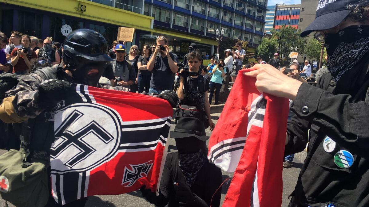 Counter-protesters tear a Nazi flag Saturday, at a rally in Portland, Ore., by far-right demonstrators.