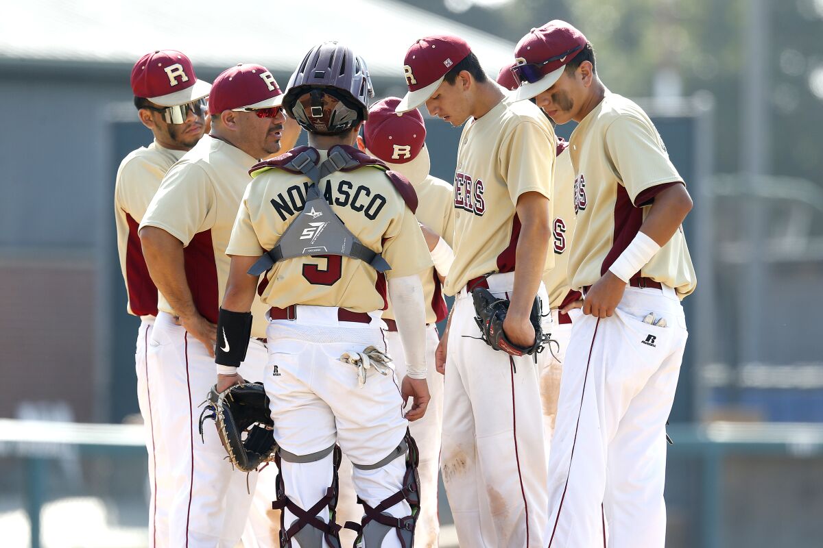Roosevelt High baseball players gather on the mound to discuss strategy.