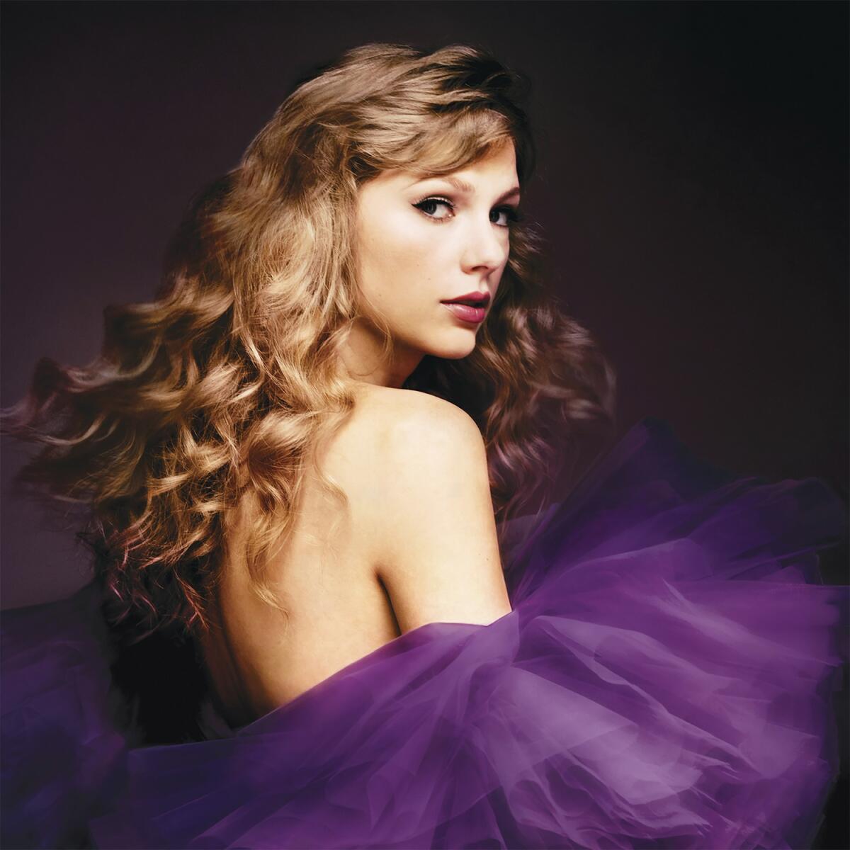 Taylor Swift wears a puffy purple dress as she looks over her right shoulder to pose for a photo