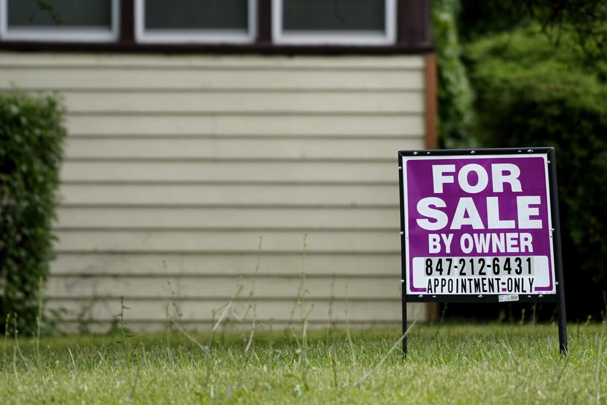 A for sale sign in the grass in front of a house 