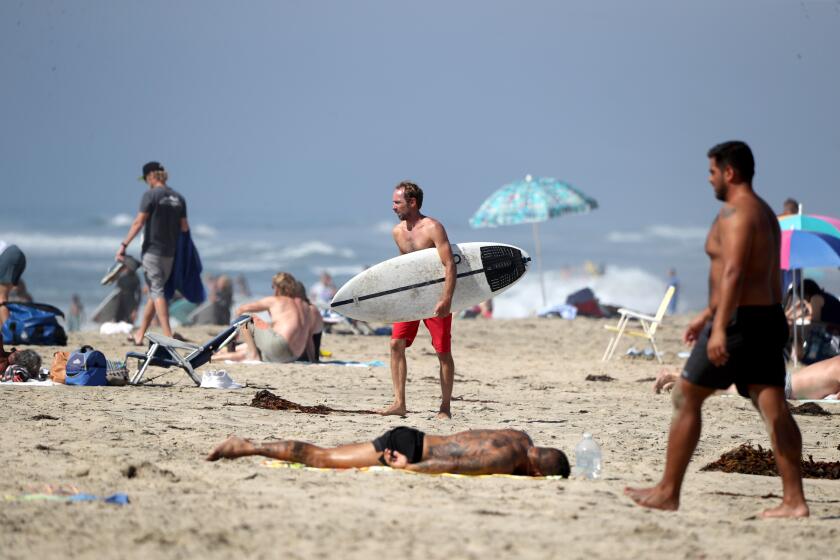 People enjoy a day at the beach on a warm sunny day near the Huntington Beach Pier, in Huntington Beach on Friday, Oct. 16, 2020.