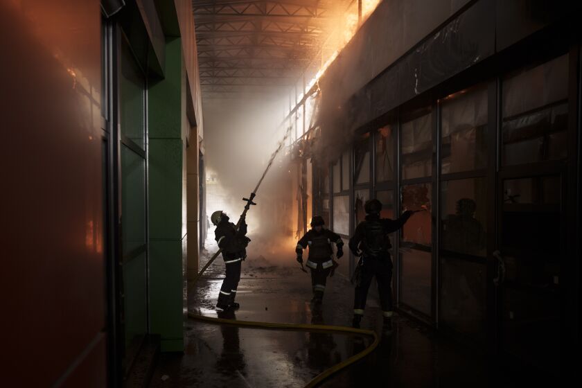Firefighters work to extinguish a fire at a shop following a Russian bombardment in Kharkiv, Ukraine, Friday, April 22, 2022. (AP Photo/Felipe Dana)