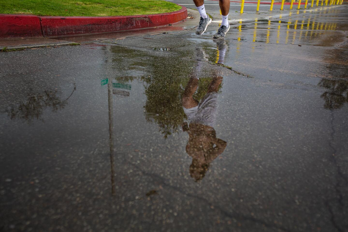 A jogger runs in the rain at the Rose Bowl Loop on Thursday in Pasadena.