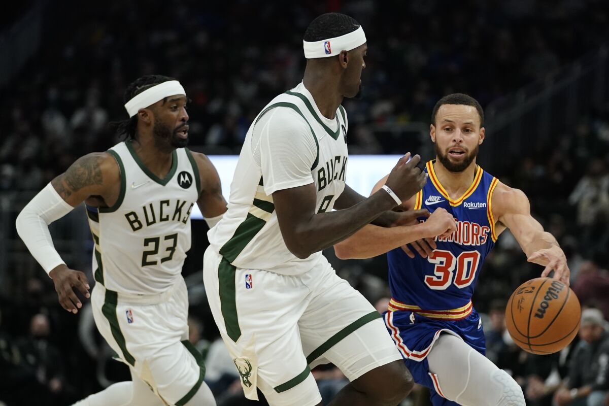 Golden State Warriors' Stephen Curry looks to pass around Milwaukee Bucks' Bobby Portis and Wesley Matthews during the first half of an NBA basketball game Thursday, Jan. 13, 2022, in Milwaukee. (AP Photo/Morry Gash)