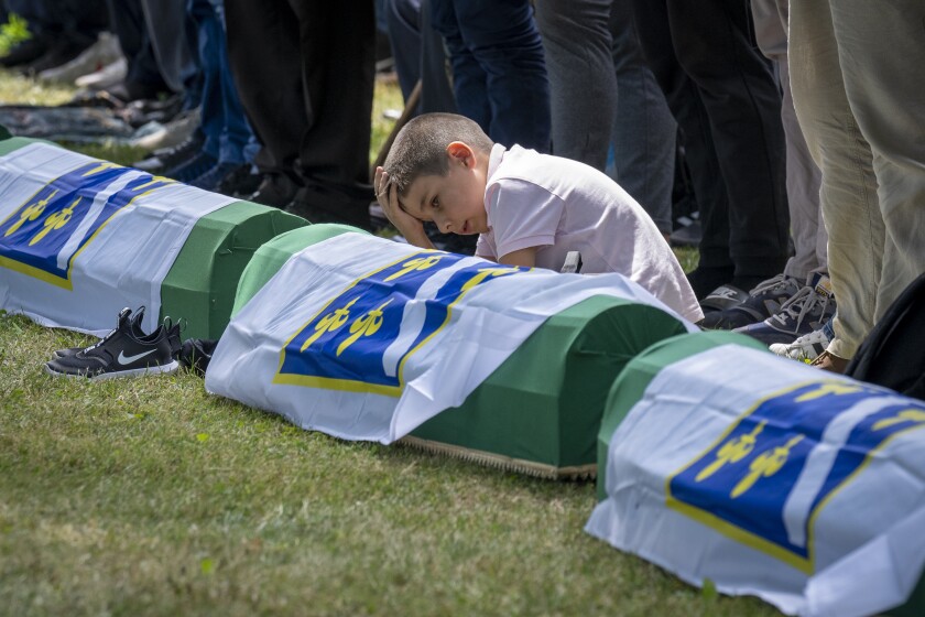 A boy reacts as mourners prepare for the funeral of newly identified victims at the memorial cemetery in Potocari near Srebrenica, Bosnia, Sunday, July 11, 2021. Bosnia is marking the 26th anniversary of the Srebrenica massacre, the only episode of its 1992-95 fratricidal war that has been declared a genocide by international and national courts. The brutal execution of more than 8,000 Muslim Bosniaks by Bosnian Serb troops is being commemorated by a series of events Sunday. (AP Photo/Darko Bandic)