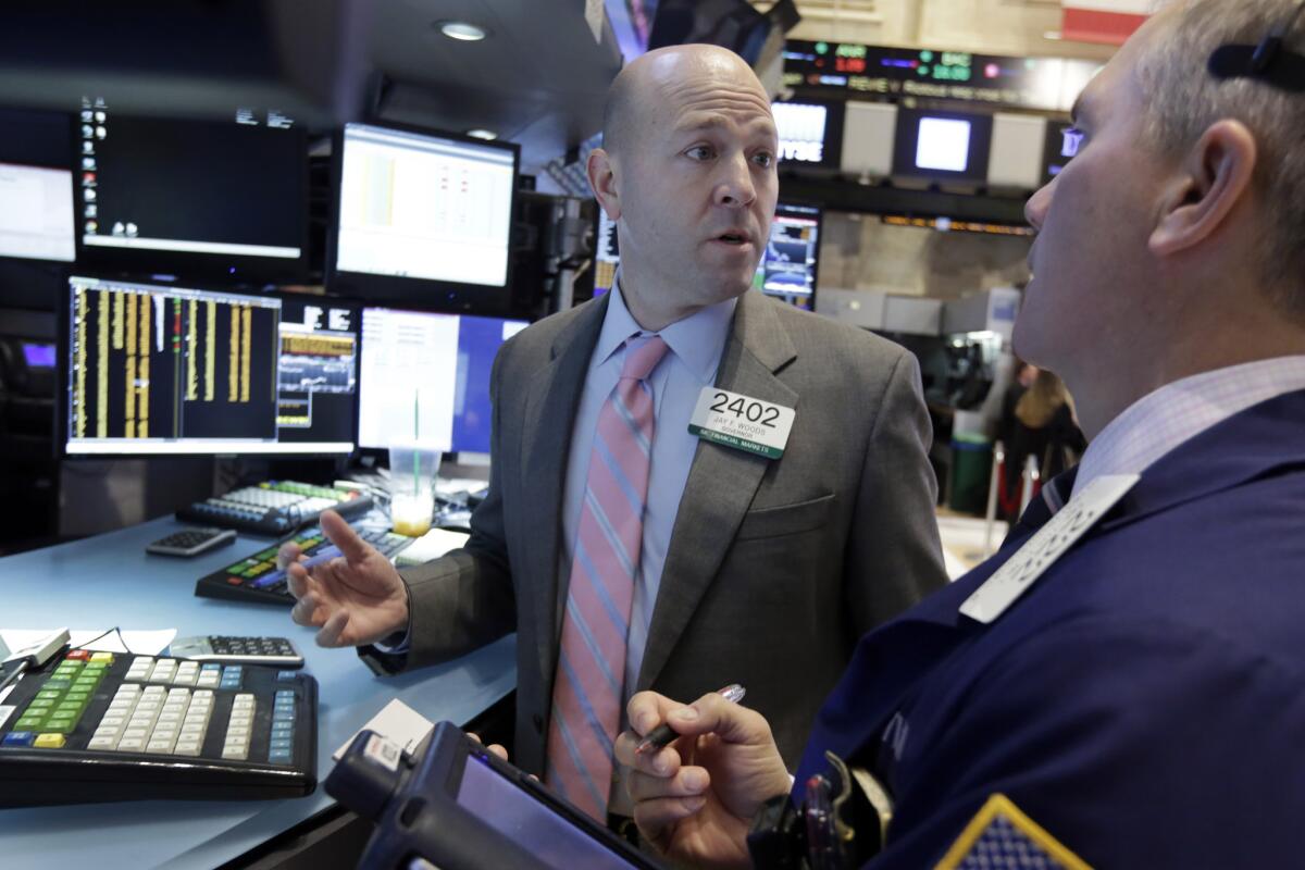 Jay Woods, left, works at his post Friday on the floor of the New York Stock Exchange.