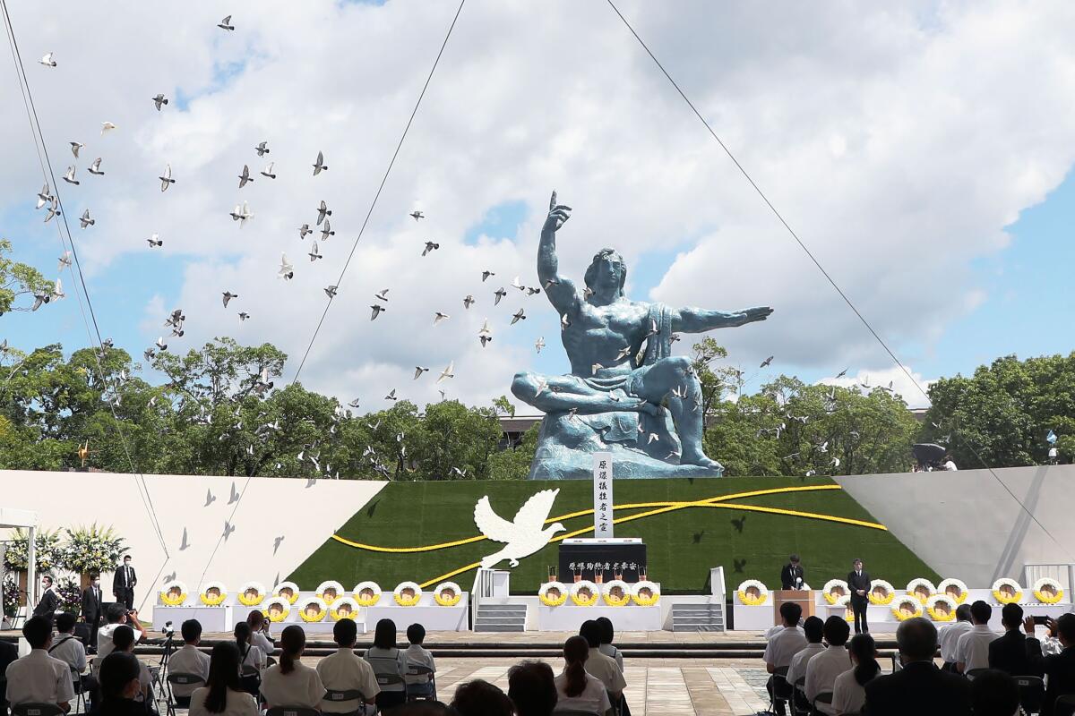 Doves fly over the Statue of Peace during a ceremony at Nagasaki Peace Park in Nagasaki, southern Japan Monday, Aug. 9, 2021. The Japanese city of Nagasaki on Monday marked its 76th anniversary of the U.S. atomic bombing. (Kyodo News via AP)