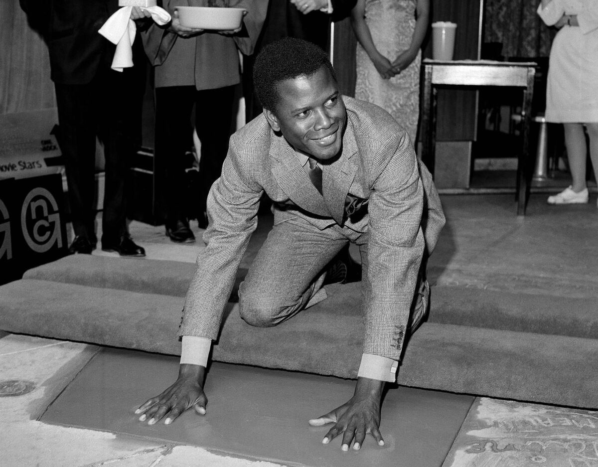 FILE - Sidney Poitier, star of "To Sir With Love," places his hands in wet cement at Grauman's Chinese Theater in Los Angeles on June 23, 1967. Poitier, the groundbreaking actor and enduring inspiration who transformed how Black people were portrayed on screen, became the first Black actor to win an Academy Award for best lead performance and the first to be a top box-office draw, died Thursday, Jan. 6, 2022 in the Bahamas. He was 94. (AP Photo/File)