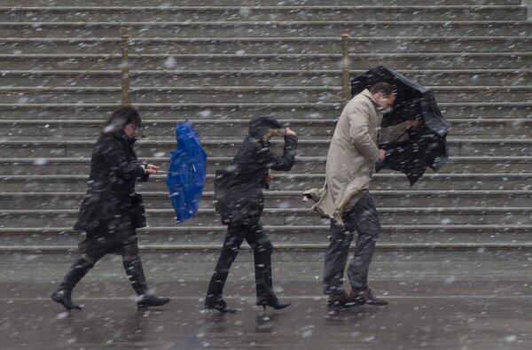 People walk as snow falls during a late-winter storm in Washington, D.C., on Wednesday. Federal offices and many schools have closed in preparation for a mix of snow, sleet and rain that could account for the area's largest winter storm in two years.