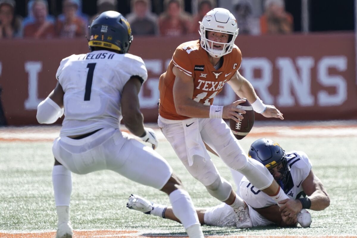 Texas' Sam Ehlinger (11) scrambles against West Virginia's Dylan Tonkery (10) and Tony Fields II (1) during the first half of an NCAA college football game in Austin, Texas, Saturday, Nov. 7, 2020. (AP Photo/Chuck Burton)