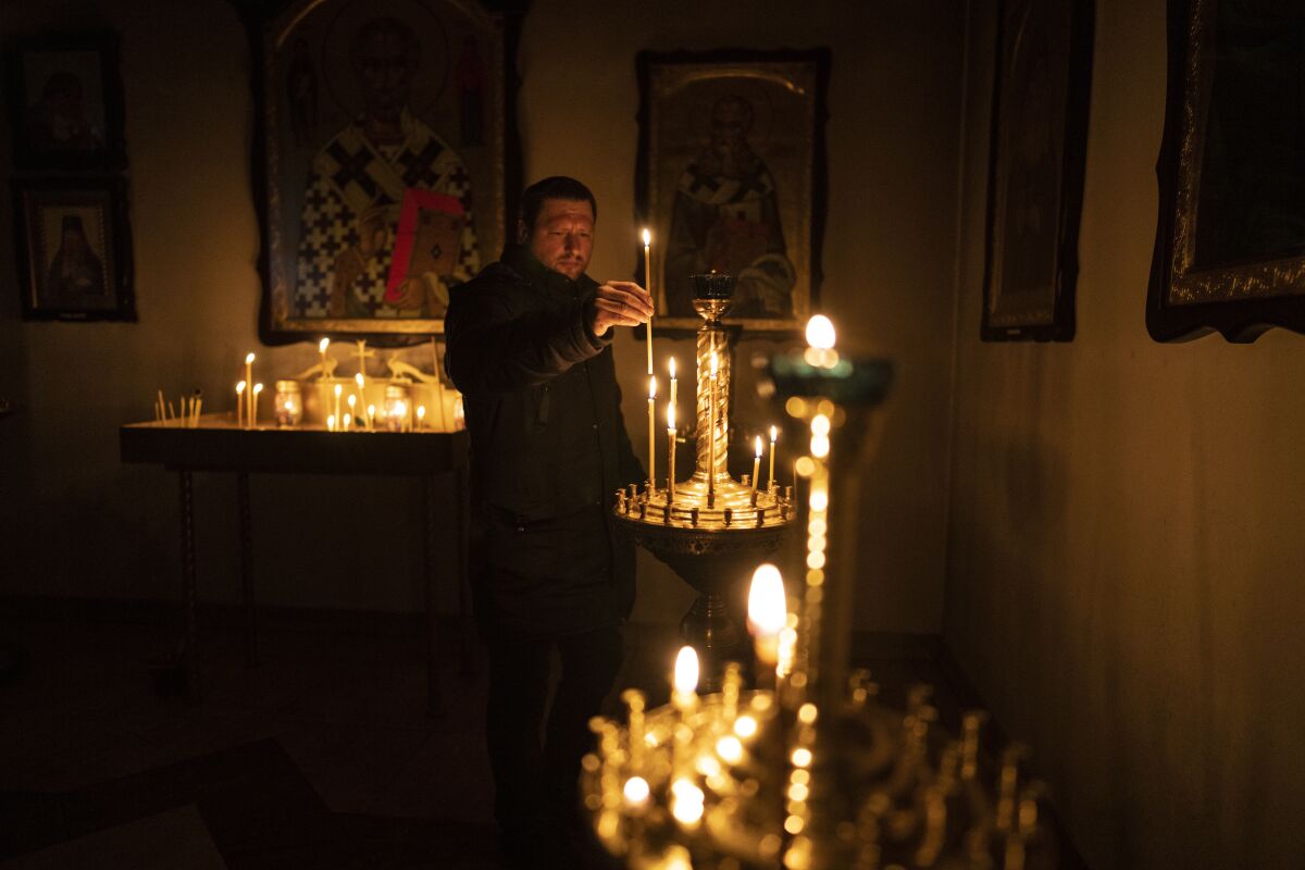 A man lights a candle during a Sunday service in an Orthodox church in Bucha, in the outskirts of Kyiv, Ukraine, Sunday, April 10, 2022. (AP Photo/Rodrigo Abd)