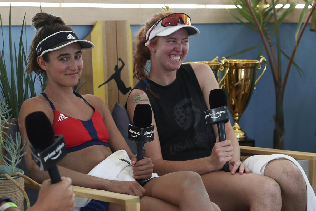 This 2020, photo provided by the Association of Volleyball Professionals shows Sarah Sponcil, left, and Kelly Claes during an interview at the AVP Champions Cup in Long Beach, Calif. The Americans are part of the first generation of college beach volleyball players to reach the Olympics. At 24 and 25, they are the youngest U.S. beach team ever to qualify for the Summer Games. (Mpu Dinani/AVP via AP)