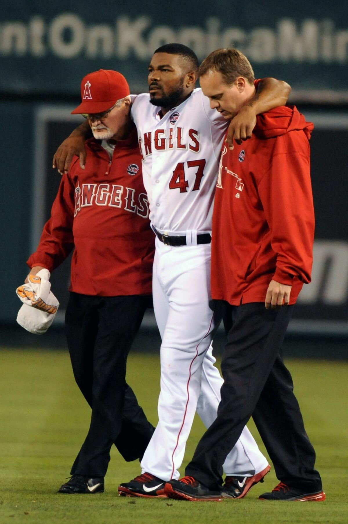 Angels second baseman Howie Kendrick, center, is helped off the field by team trainers Adam Nevala, left, and Rick Smith after suffering a knee injury during Monday's loss to the Texas Rangers.