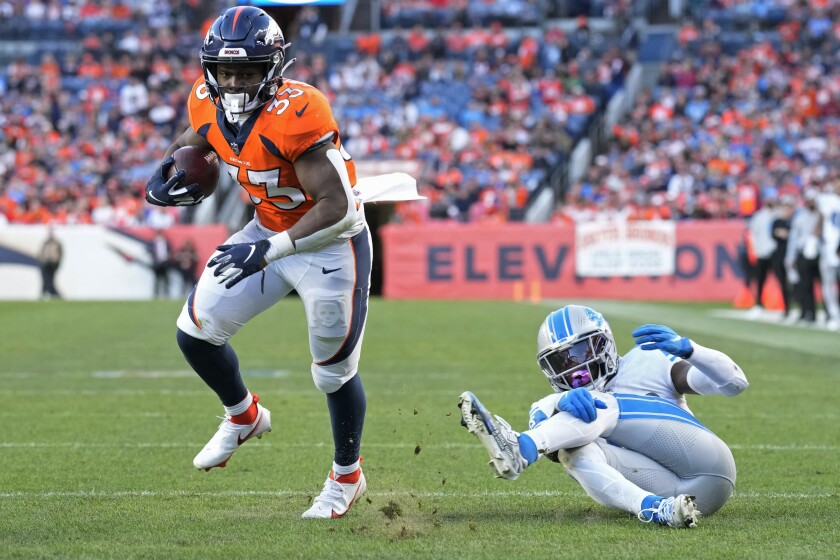 Denver Broncos running back Javonte Williams (33) avoids a tackle by Detroit Lions safety Jalen Elliott (42) before running in for a touchdown during the second half of an NFL football game, Sunday, Dec. 12, 2021, in Denver. (AP Photo/David Zalubowski)