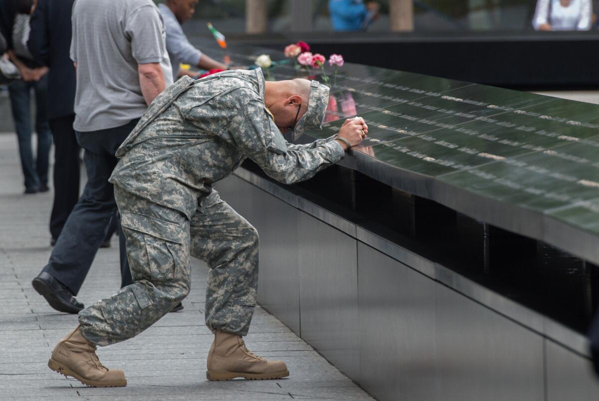 Army Sgt. Edwin Morales prays during a ceremony at the World Trade Center site in New York. With a moment of silence and somber reading of names, victims' relatives began marking the 14th anniversary of Sept. 11 in a subdued gathering Friday at ground zero.