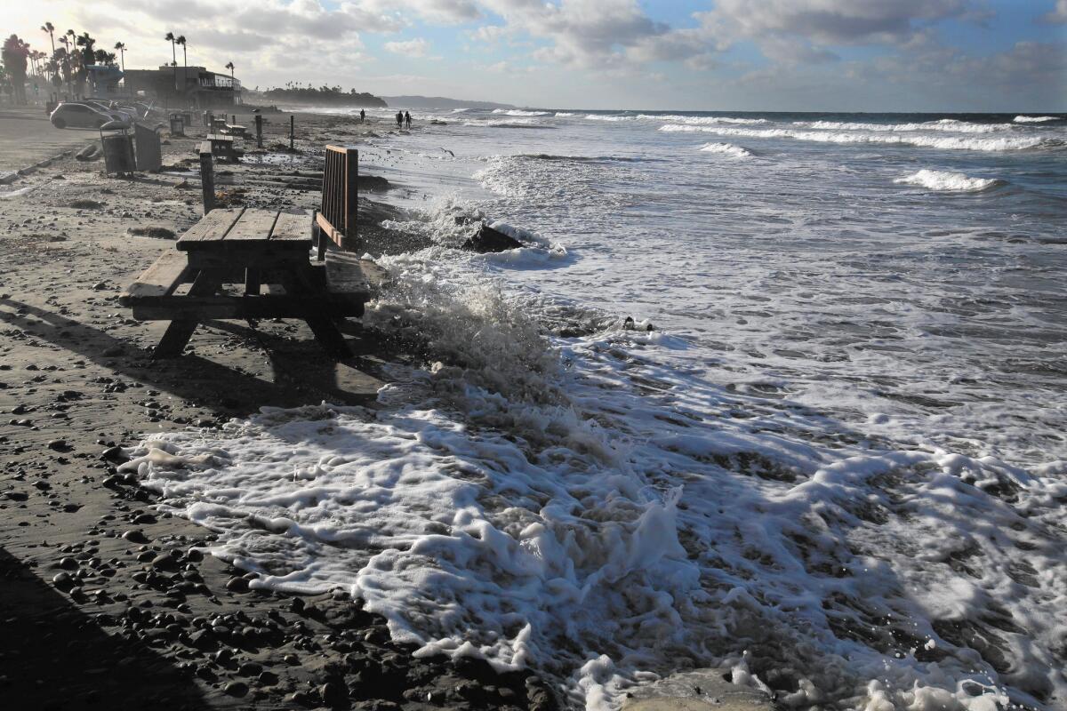 Extreme high tide and wind-whipped swells brought the ocean up over barriers and against sea walls along the San Diego County coastline.