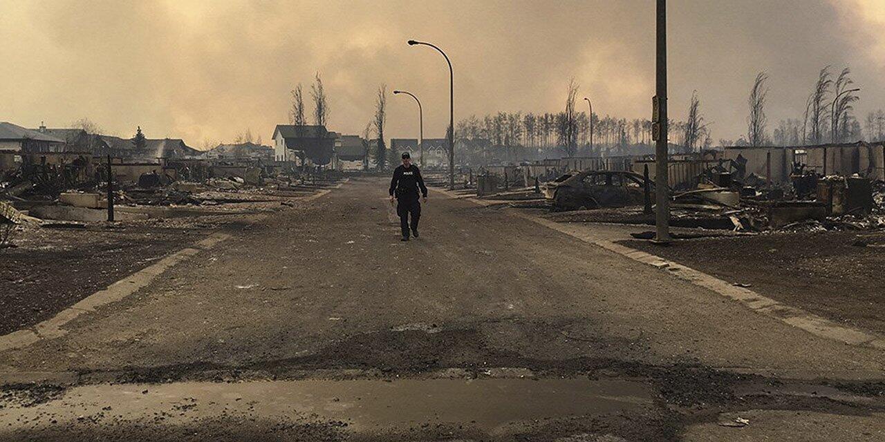 A Mountie surveys the damage on a street in Fort McMurray, Alberta, Canada after a wildfire moved through the region, prompting the evacuation of all the residents.