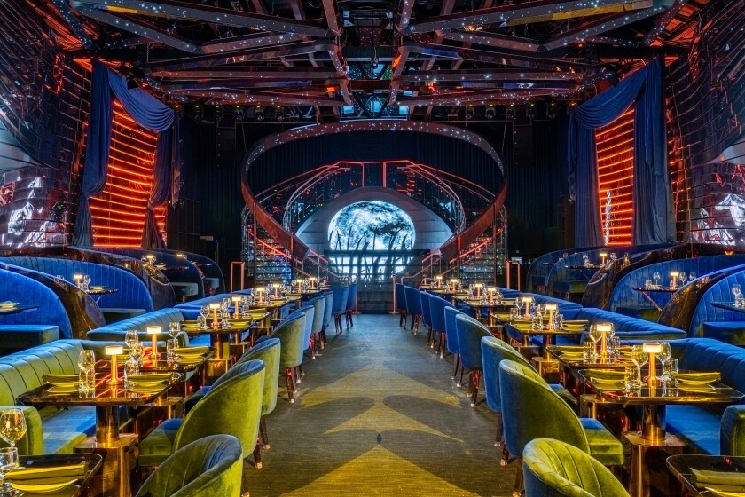 The main dining room and stage at MainRo, which features two long dining tables running the length of the room.