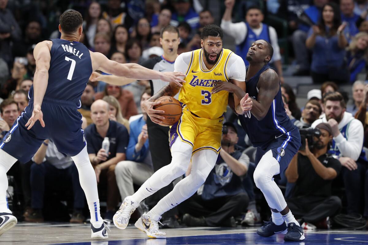 The Lakers' Anthony Davis, who scored 31 points, drives against the Mavericks' Dwight Powell and Dorian Finney-Smith.