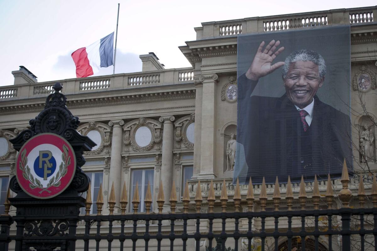A giant portrait of late South African President Nelson Mandela hangs on the facade of the French Foreign Ministry in Paris. Flags lowered to half-staff, days of mourning and other tributes to the anti-apartheid fighter, who died Thursday at his home in a Johannesburg suburb, have poured out from every corner of the world.