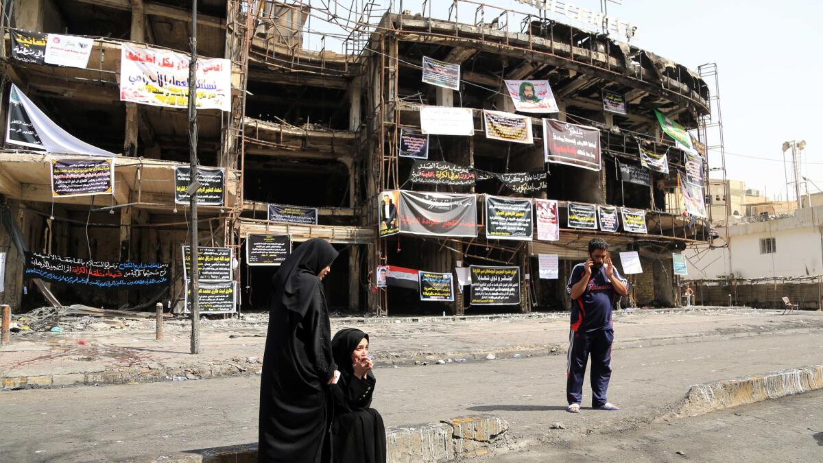 Iraqi women wait on Tuesday for news of family members missing after Sunday's deadly truck bombing in the Karada neighborhood of Baghdad.