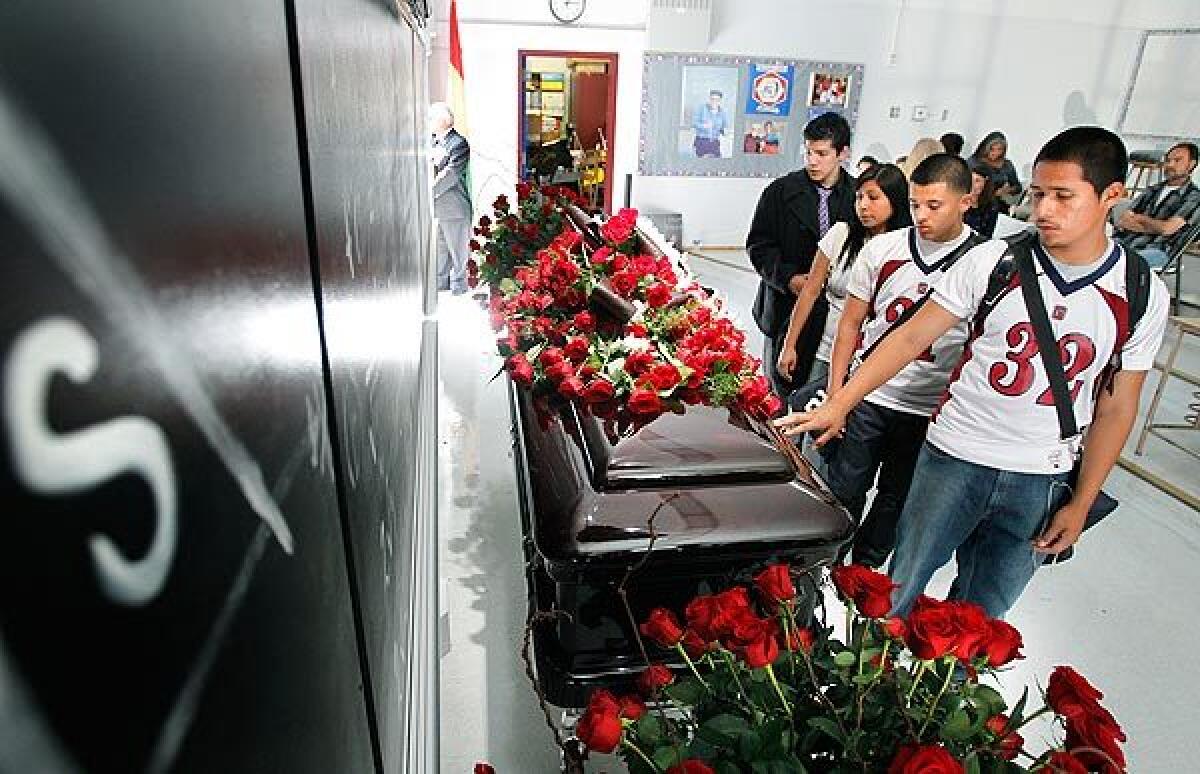 Members of Garfield's junior varsity football team touch Escalante's casket. See full story