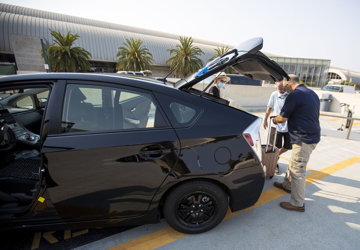 Uber driver Arad Aryan helps Jeff and Christy Labarthe with their luggage at John Wayne Airport on Thursday, Aug. 20.