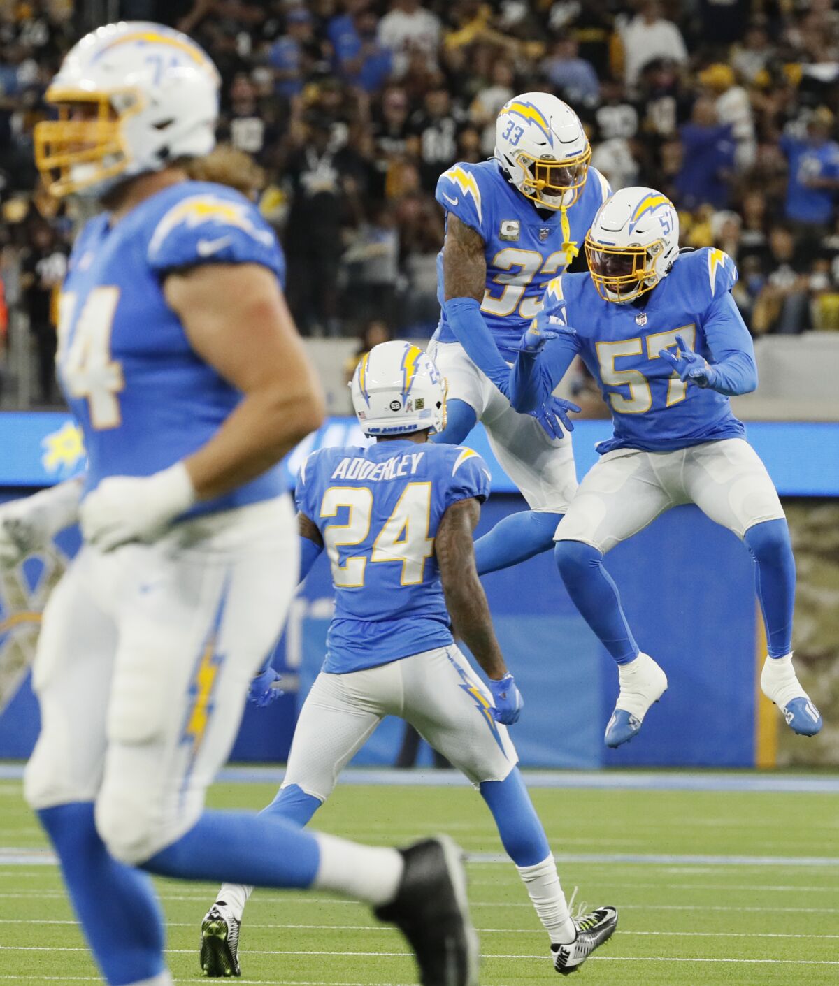 Chargers free safety Derwin James and inside linebacker Amen Ogbongbemiga jump in the air and celebrate.