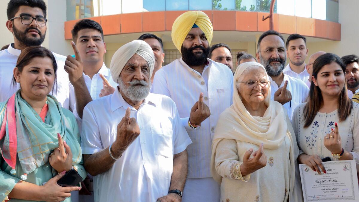 Indian Congress Party candidate Gurjeet Singh Aujla, center, and family members show their ink-marked fingers after casting their vote Sunday in Amritsar.