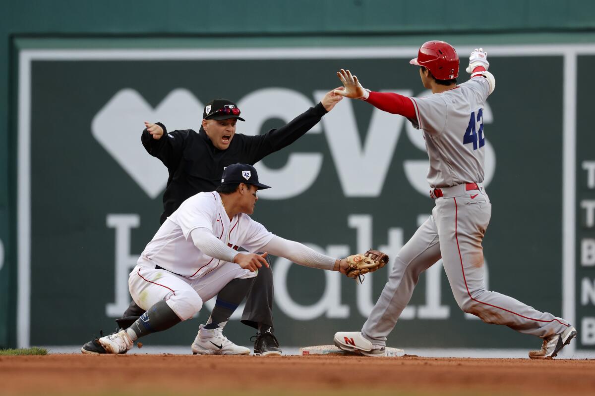 The Angels' Shohei Ohtani gestures that he's safe ahead of a tag by Red Sox shortstop Yu Chang.