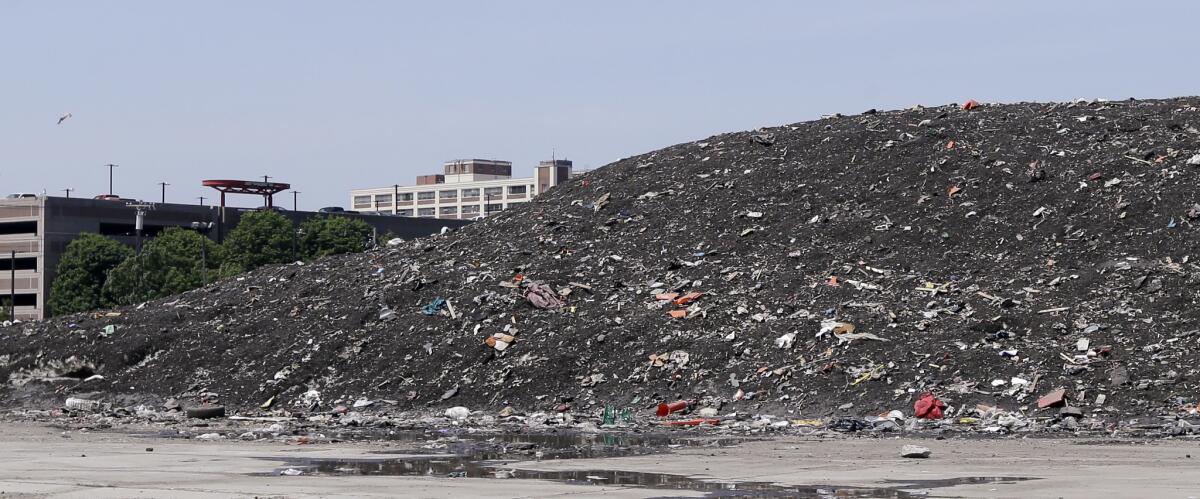 Debris covers a lingering snow pile, amassed during the record-setting winter, in the Seaport District in Boston.