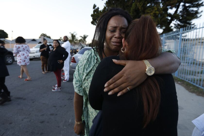 COMPTON, CA JANUARY 25, 2019: Standing on the sidewalk, wearing a hospital gown and no shoes Amira Webster, left, of Texas Arcana hugs a woman in Compton, CA January 25, 2019. Amira brother was killed and two others were wounded early this afternoon in a shooting outside of a church in Compton where a funeral was taking place. They were attending the funeral of a family member. Amira is pregnaunt and when the shooting happened her water broke and she was taken to the hospital. (Francine Orr/ Los Angeles Times)