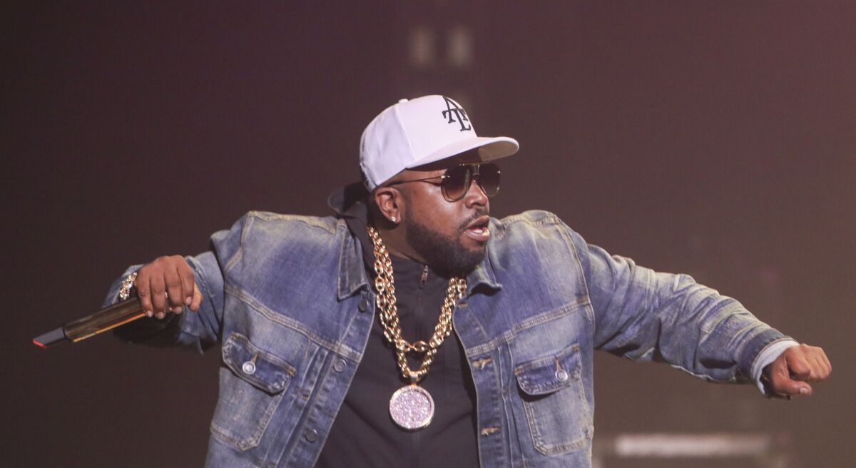 Big Boi dans une veste en jean tenant un microphone et rappant sur scène