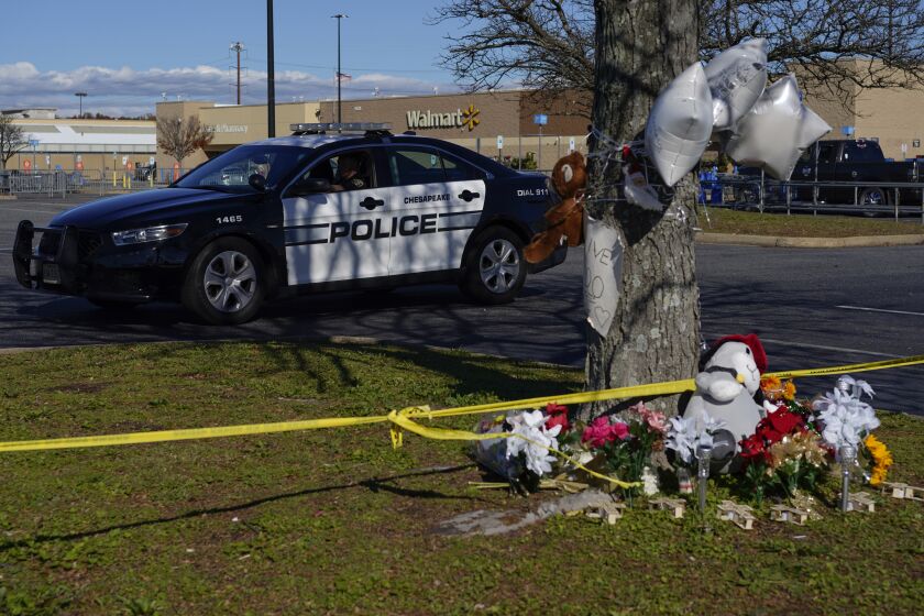 FILE - A police vehicle drives past a makeshift memorial in the parking lot of a Walmart in Chesapeake, Va., Nov. 28, 2022, for the six people killed at the Walmart when a manager opened fire with a handgun before an employee meeting on Nov. 22. The last two patients who were wounded during the shooting have been released from the hospital. (AP Photo/Carolyn Kaster, File)