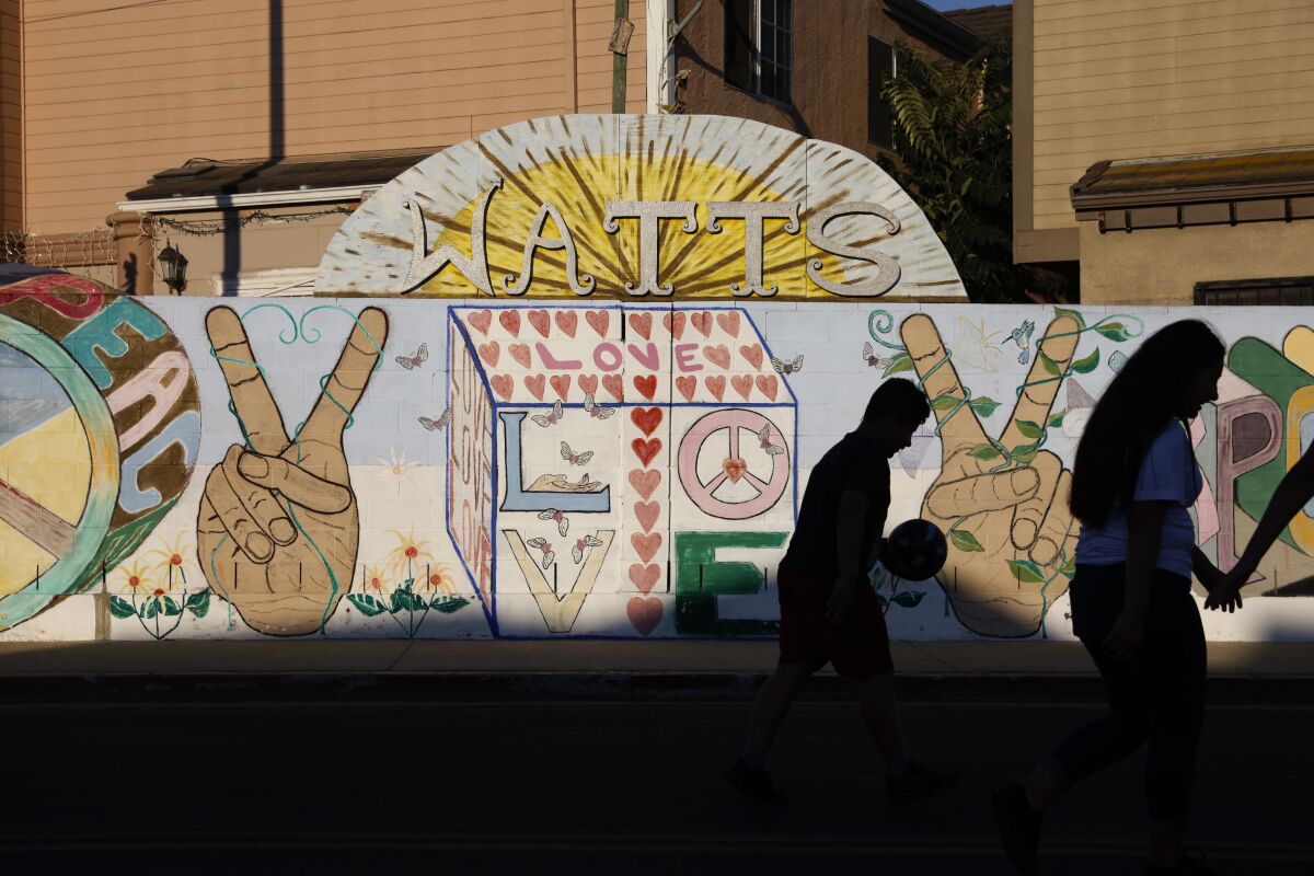 Edwin Talavera walks with a ball as he heads back to home after playing soccer with his sister, Samantha, right, in the Watts neighborhood of Los Angeles, Thursday, June 11, 2020. Watts has changed demographically from an exclusively Black neighborhood in the '60s to one that's majority Latino. But it remains a poor neighborhood with high unemployment. (AP Photo/Jae C. Hong)