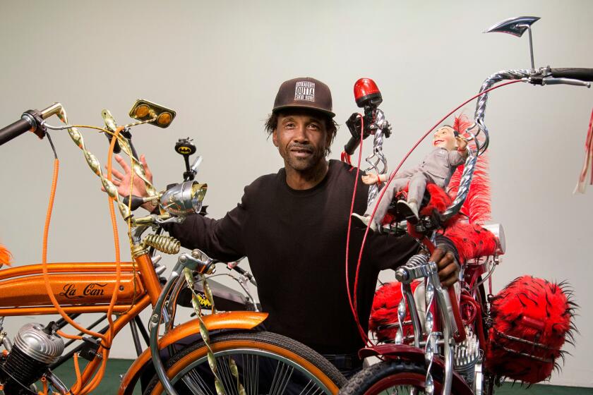 Skid Row artist and activist General Dogon posing with his custom bikes at the Los Angeles Poverty Department's Skid Row History Museum and Archive.