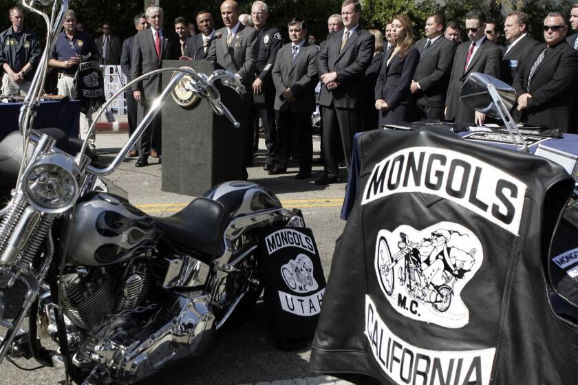 FILE - In this Oct. 21, 2008 file photo, Los Angeles County Sheriff Lee Baca, at podium, speaks during a news conference in Los Angeles. A vest with the trademarked Mongols logo is seen on a motorcycle at right. A federal jury has found the club guilty of racketeering and conspiracy, opening the way for the government to seize its trademarked logo. Jurors in Orange County ruled Thursday, Dec. 13, 2018, against the Mongol Nation, the entity that owns the image of a Mongol warrior on a motorcycle. (AP Photo/Ric Francis, File)