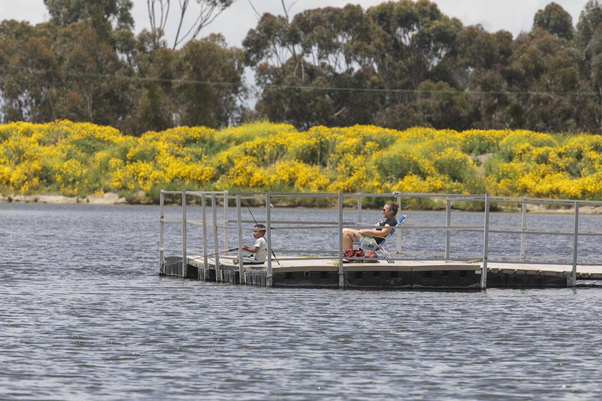 Erin Rose and her 4-year-old son Jaxon practice social distancing as they fish from a pier at the newly reopened Chollas Lake Park in San Diego on April 21.